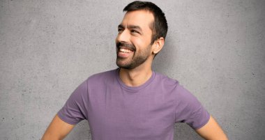 Yakışıklı adam kalça silah ile poz ve dokulu duvar üzerinde gülüyor