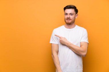 Bir ürün sunmak için yan işaret kahverengi duvar üzerinde Redhead adam