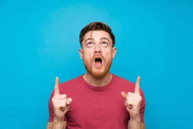 İşaret parmağı ile işaret izole mavi duvarda Redhead adam harika bir fikir
