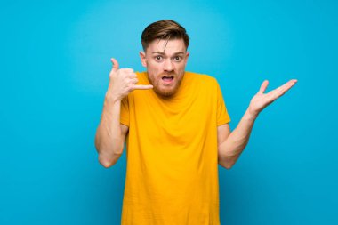 Mavi duvar üzerinde Redhead adam telefon jest yapma ve şüphe