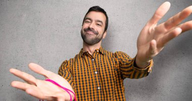 Sunan ve dokulu duvar üzerinde el ile gelmek için davet alışveriş çantaları ile adam