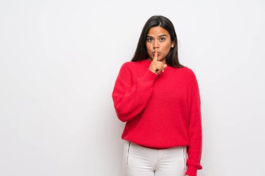 Kırmızı kazaklı genç Kolombiyalı kız sessizlik işareti gösteriyor. Parmağını ağzına sok.