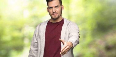 Bir parkta iyi bir anlaşma kapatmak için el sallayarak Sweatshirt ile adam