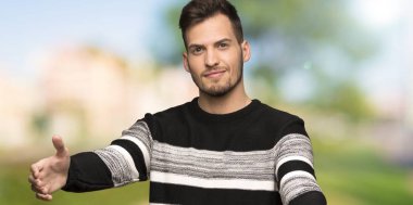 Yakışıklı adam sunumu ve açık havada el ile gelmek için davet