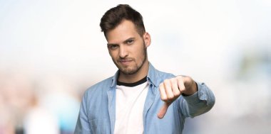 Yakışıklı adam açık havada başparmak dowg negatif ifade ile gösterilen