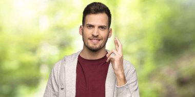 Parmakları ile Sweatshirt ile adam geçiş ve bir parkta en iyi isteyen