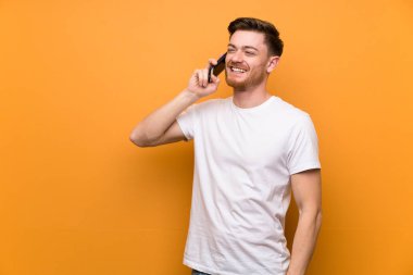 Kahverengi duvar üzerinde Redhead adam cep telefonu ile bir konuşma tutmak