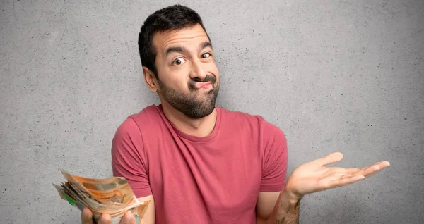 Man taking a lot of money unhappy and frustrated with something because not understand something over textured wall