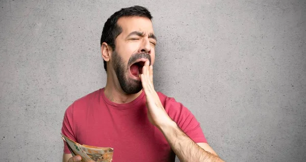 Adam esneme ve dokulu duvar üzerinde el ile geniş açık ağız kapsayan çok para alarak