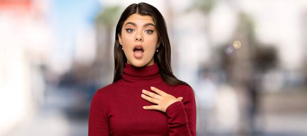 Teenager girl with turtleneck surprised and shocked while looking right at outdoors