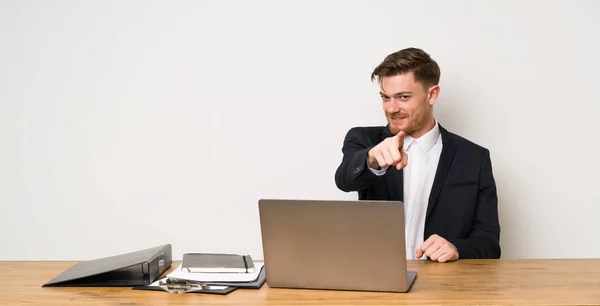 Businessman in a office points finger at you with a confident expression