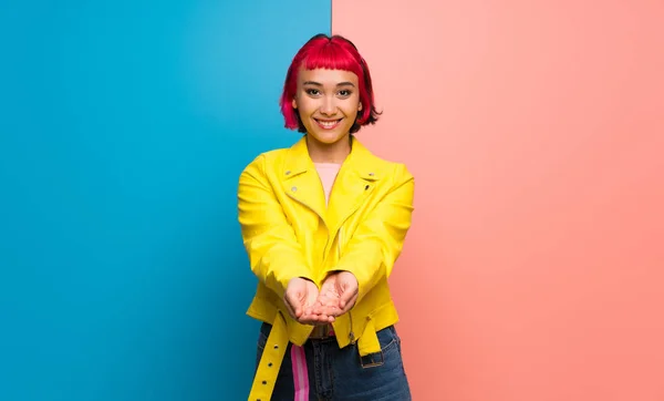 Young woman with yellow jacket holding copyspace imaginary on the palm to insert an ad