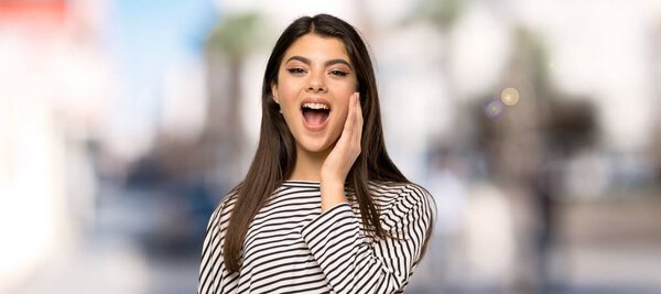 Teenager girl with striped shirt with surprise and shocked facial expression at outdoors