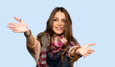 Genç hippi kadın sunum ve izole mavi arka plan üzerinde el ile gelmek için davet