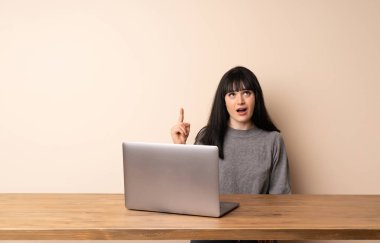 Dizüstü bilgisayarıyla çalışan genç bir kadın yukarı bakıyor ve şaşırıyor.