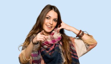 Genç hippi kadın telefon jest yapma ve izole mavi arka plan üzerinde ön işaret