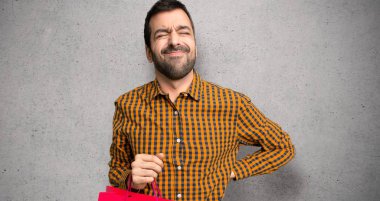 Dokuma duvar üzerinde bir çaba vardı için sırt ağrısı muzdarip alışveriş çantaları ile adam