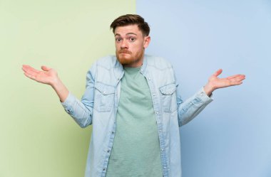 El kaldırırken şüpheleri olan renkli arka plan üzerinde Redhead adam