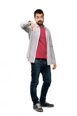 Başparmak aşağı ile negatif ifade izole beyaz arka plan üzerinde gösterilen sakallı yakışıklı adam tam uzunlukta atış