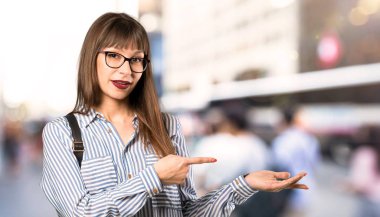 Açık havada bir reklam eklemek için avuç içinde boşaltmak hayali tutan gözlük kadın