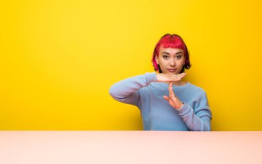 Pembe saçlı genç bir kadın zaman harcıyor.