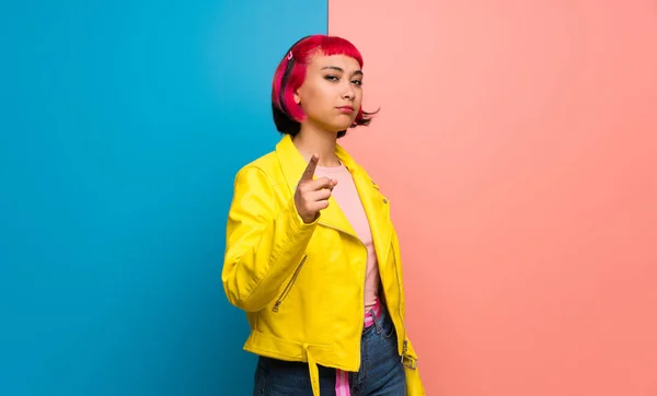 Young woman with yellow jacket serious and pointing to the front