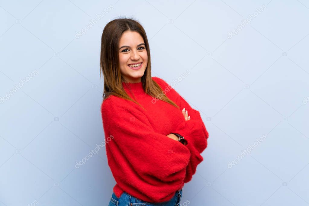 Young woman over isolated blue wall with arms crossed and looking forward