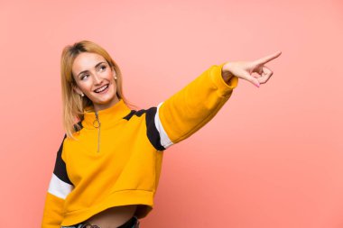 Soyutlanmış pembe arka planı olan genç sarışın kadın.