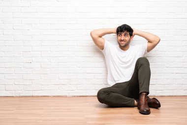 Katta oturan genç adam sinirli ve ellerini başının üstüne alır