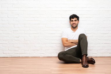 Kolların frontal pozisyonda kesişmiş olduğu yerde oturan genç adam