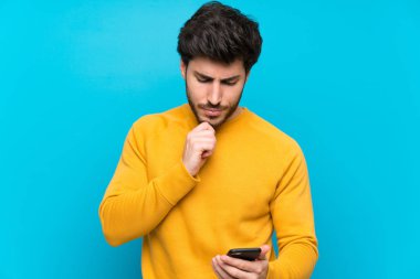 Izole mavi duvar düşünme ve bir mesaj gönderme üzerinde Yakışıklı