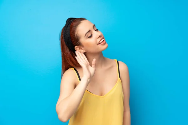 Young Redhead Woman Blue Background Listening Something Putting Hand Ear — Stock Photo, Image
