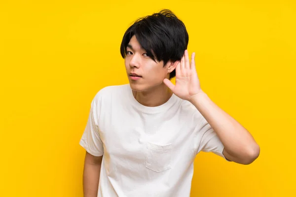 Asiático Hombre Sobre Aislado Amarillo Pared Escuchar Algo Poniendo Mano — Foto de Stock