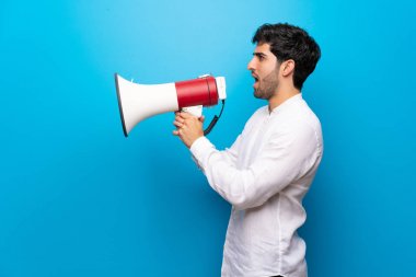 Bir megafon üzerinden bağıran izole mavi duvar üzerinde genç adam