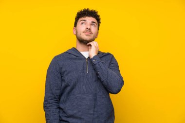 Izole sarı duvar ayakta ve bir fikir düşünme üzerinde genç adam