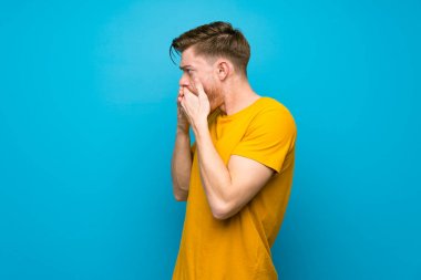 Kırmızı kafalı adam mavi duvar üzerinde ağız kapsayan ve yan bakıyor