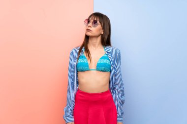 Bikinili genç bir kadın ciddi bir yüzle yukarı bakıyor.