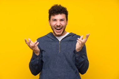 Izole sarı duvar üzerinde genç adam mutsuz ve bir şey ile sinirli