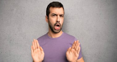 Yakışıklı adam dokulu duvar üzerinde iki eliyle stop jest yapma