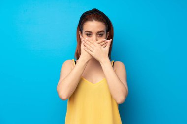 Mavi arka plan ağız uygunsuz bir şey söylediğin için elleriyle kapsayan genç Kızıl saçlı kadın