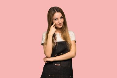 Young woman with apron looking to the front on isolated pink background