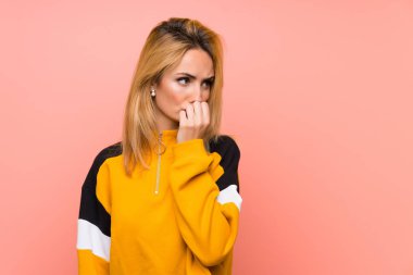 Soyutlanmış pembe arka planı olan genç sarışın bir kadın.