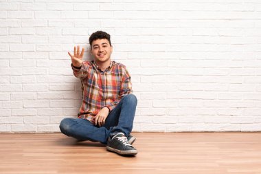 Mutlu katta oturan geri sayıma dört parmak ile genç adam