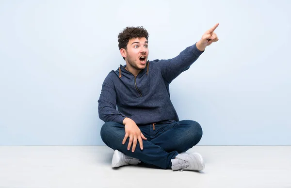 Jovem Sentado Chão Apontando Para Longe — Fotografia de Stock