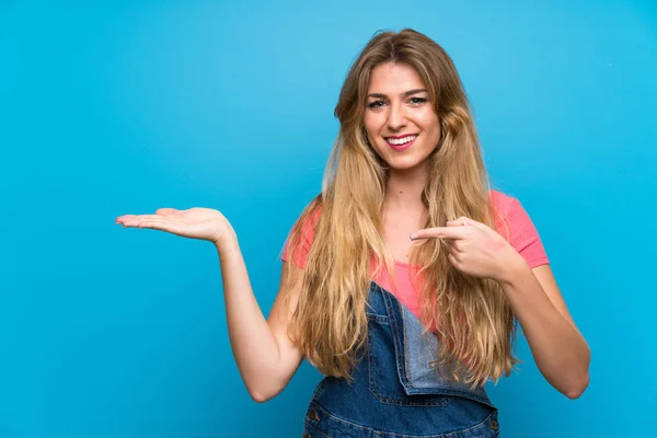 Jeune Femme Blonde Avec Salopettes Sur Mur Bleu Isolé Tenant — Photo