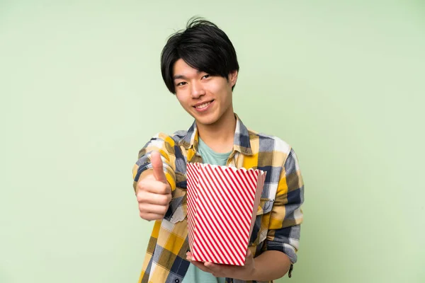 Asiático Hombre Sobre Aislado Verde Pared Celebración Bowl Palomitas Maíz — Foto de Stock