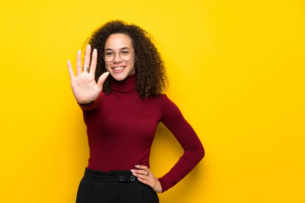 Dominican woman with turtleneck sweater counting five with fingers