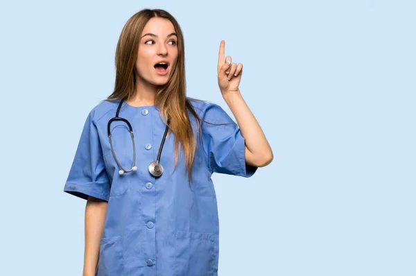 Young Nurse Intending Realizes Solution While Lifting Finger Isolated Blue — 스톡 사진