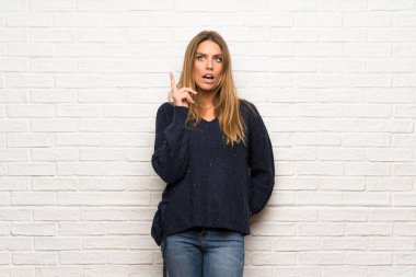 Başını çizerken bir fikir düşünme tuğla duvar üzerinde Sarışın kadın