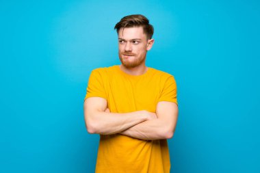Kafa karıştırıcı yüz ifadesi ile mavi duvar üzerinde Redhead adam